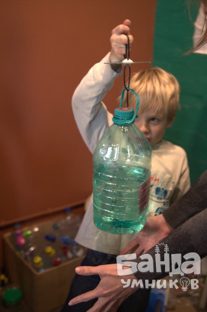 Девочка демонстрирует опыт с атмосферным давлением: вода удерживается в бутылке.