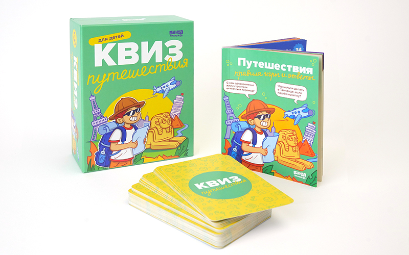 Состав настольной игры Квиз «Путешествия»: зеленая коробка, открытая книга правил и ответов и стопка игровых карточек.
